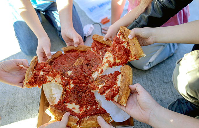 People grabbing multiple slices from a pizza